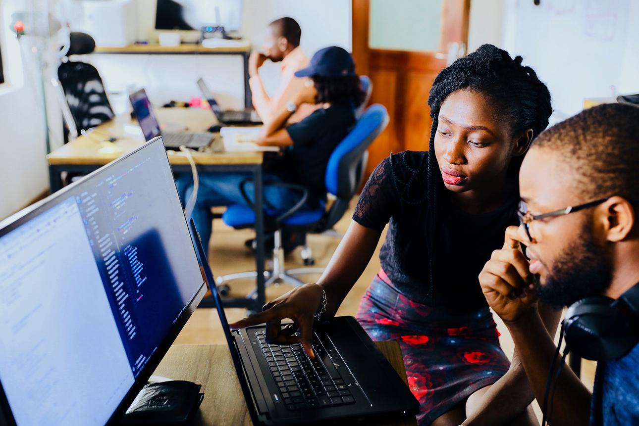 Two students looking at code on computer screen in classroom