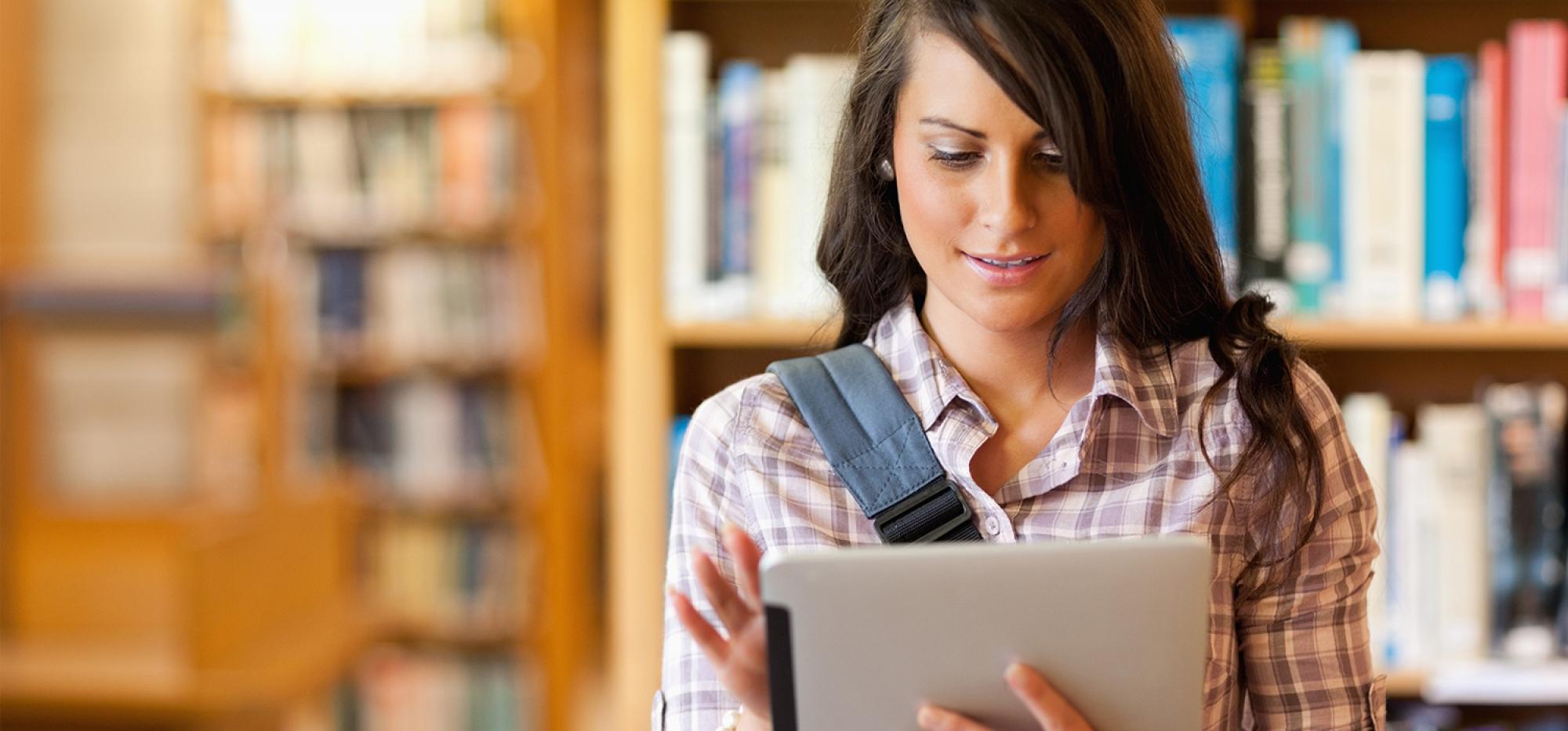Female student in library working on tablet